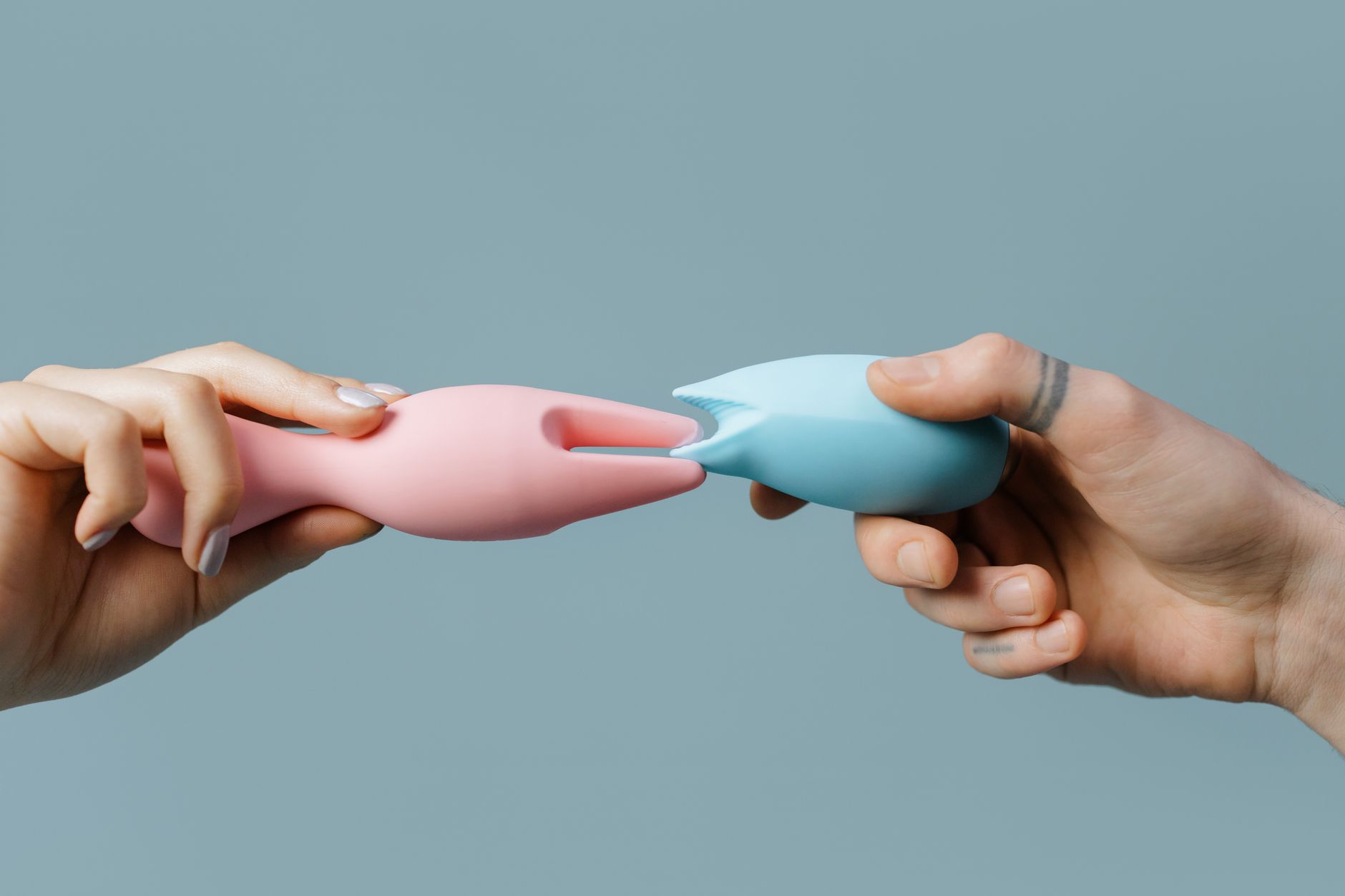 Hands holding colorful silicone toys, representing shared pleasure and intimate partnership