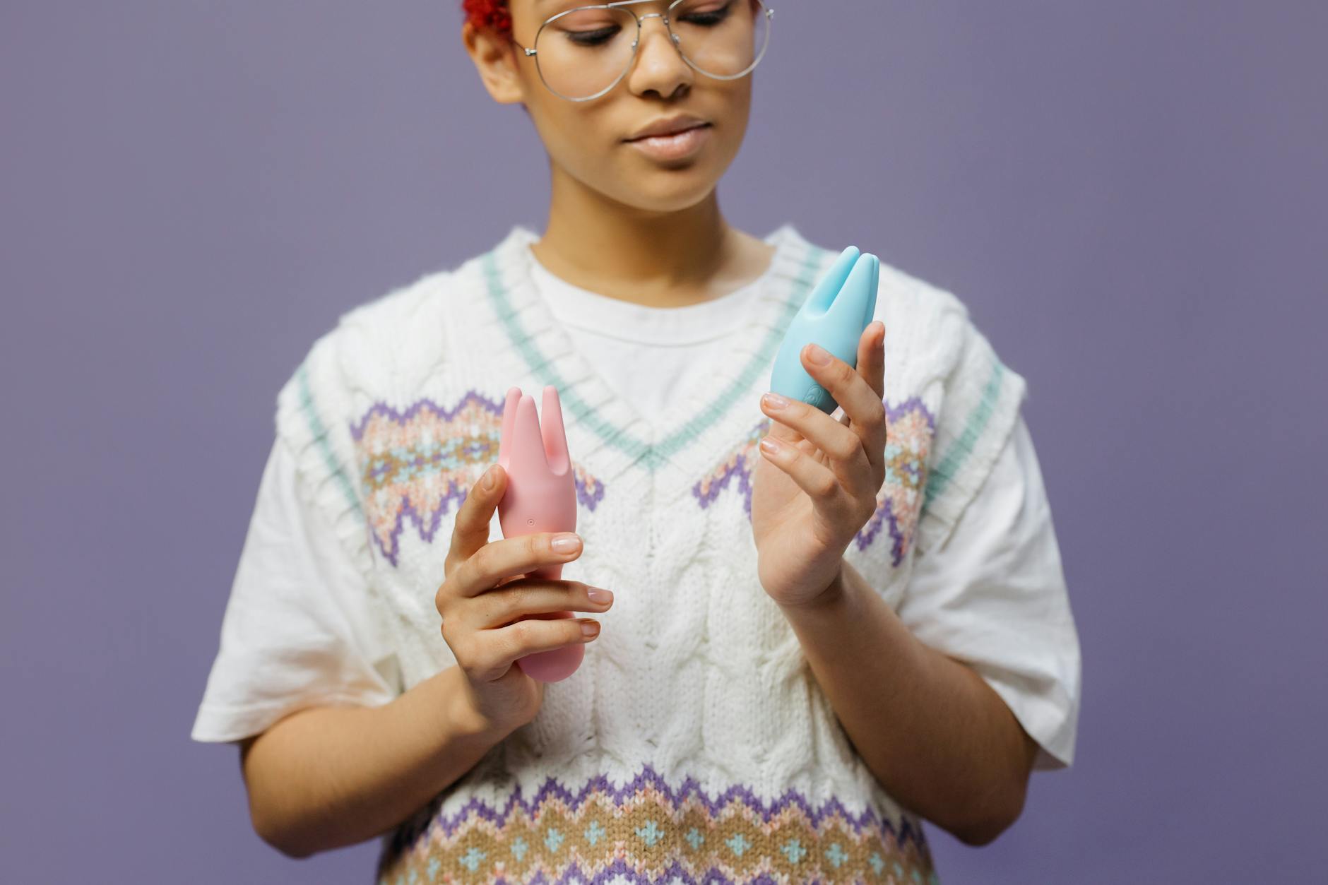 Woman holding blue and pink silicone vibrators, thinking about her pleasure on her terms.