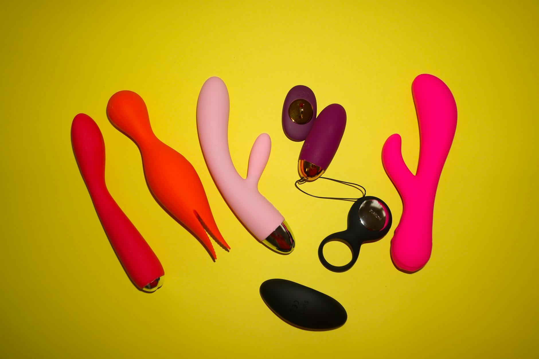 Colorful vibrators arranged on a bright yellow background, showcasing design and pleasure diversity
